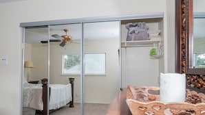 Une chambre à coucher avec un lit, une commode, un miroir et un ventilateur de plafond.