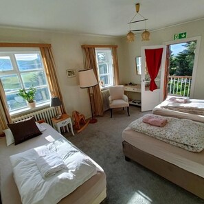 A hotel room with two beds, a desk, a chair, and a view of the outdoors.
