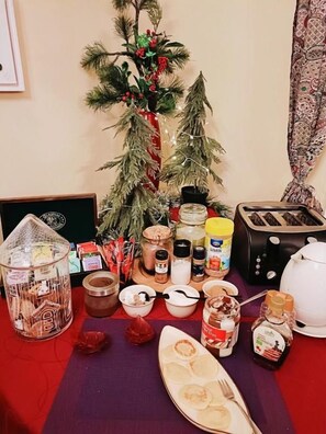A table with various food items, a small Christmas tree, and a toaster.