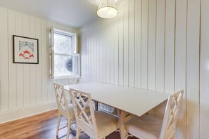 A dining area with a white table and chairs, a window with blinds, and a framed picture on the wall. - Fabulous Classic Victorian Home in Pacific Heights (San Francisco)