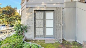 A building with a stone facade, a metal gate, and a small garden area with plants and a stepping stone. - Fabulous Classic Victorian Home in Pacific Heights (San Francisco)
