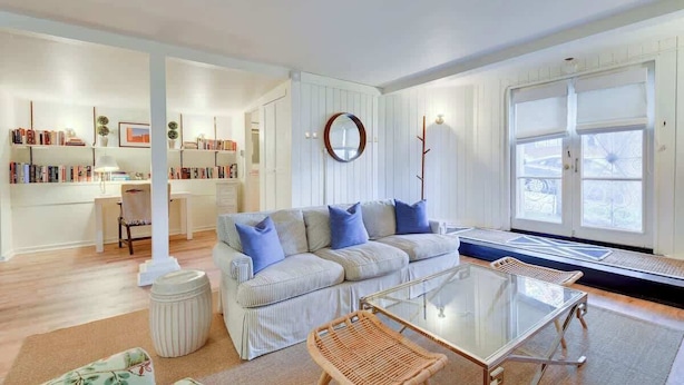 A living room with a striped sofa, a glass coffee table, and a bookshelf. - Fabulous Classic Victorian Home in Pacific Heights (San Francisco)