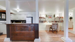 A modern kitchen with white cabinets, a wooden island, and a dining area with a chair and bookshelves. - Fabulous Classic Victorian Home in Pacific Heights (San Francisco)