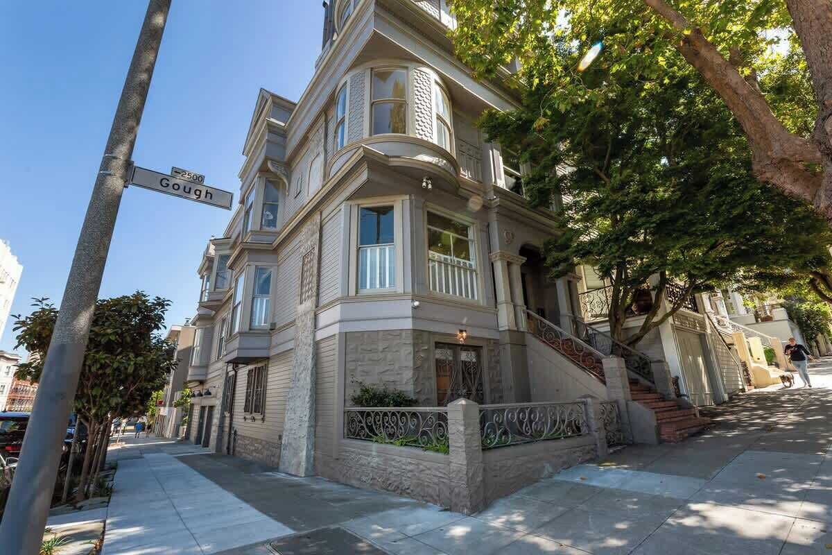 A Victorian-style building with a prominent bay window, a stone facade, and a staircase leading to the entrance.