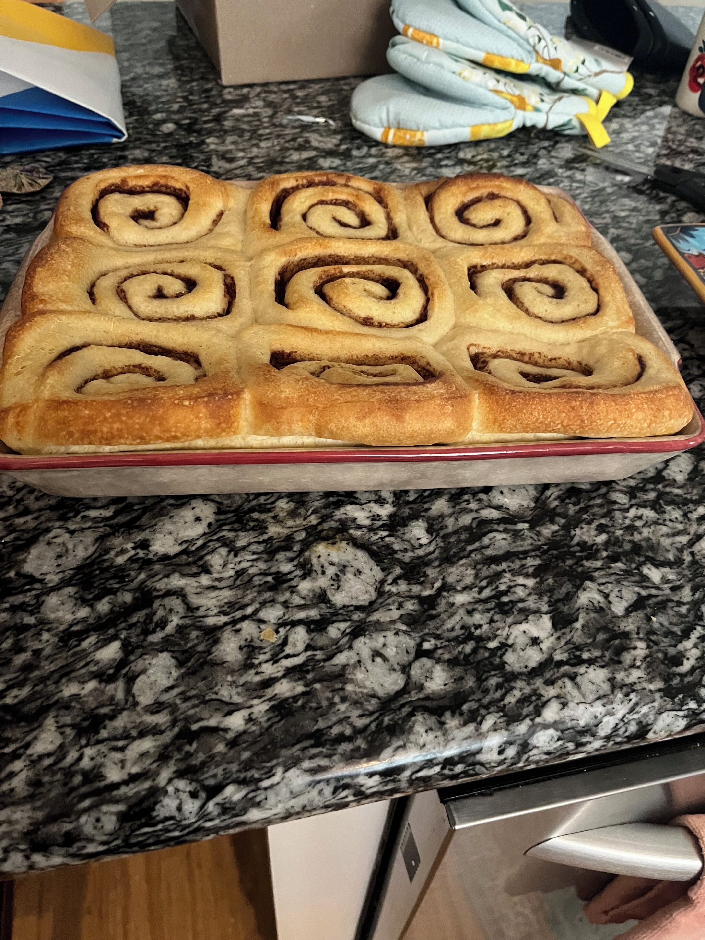 Un recipiente rectangular para hornear con un alimento horneado dorado, posiblemente una pastelería, sobre una encimera de granito.