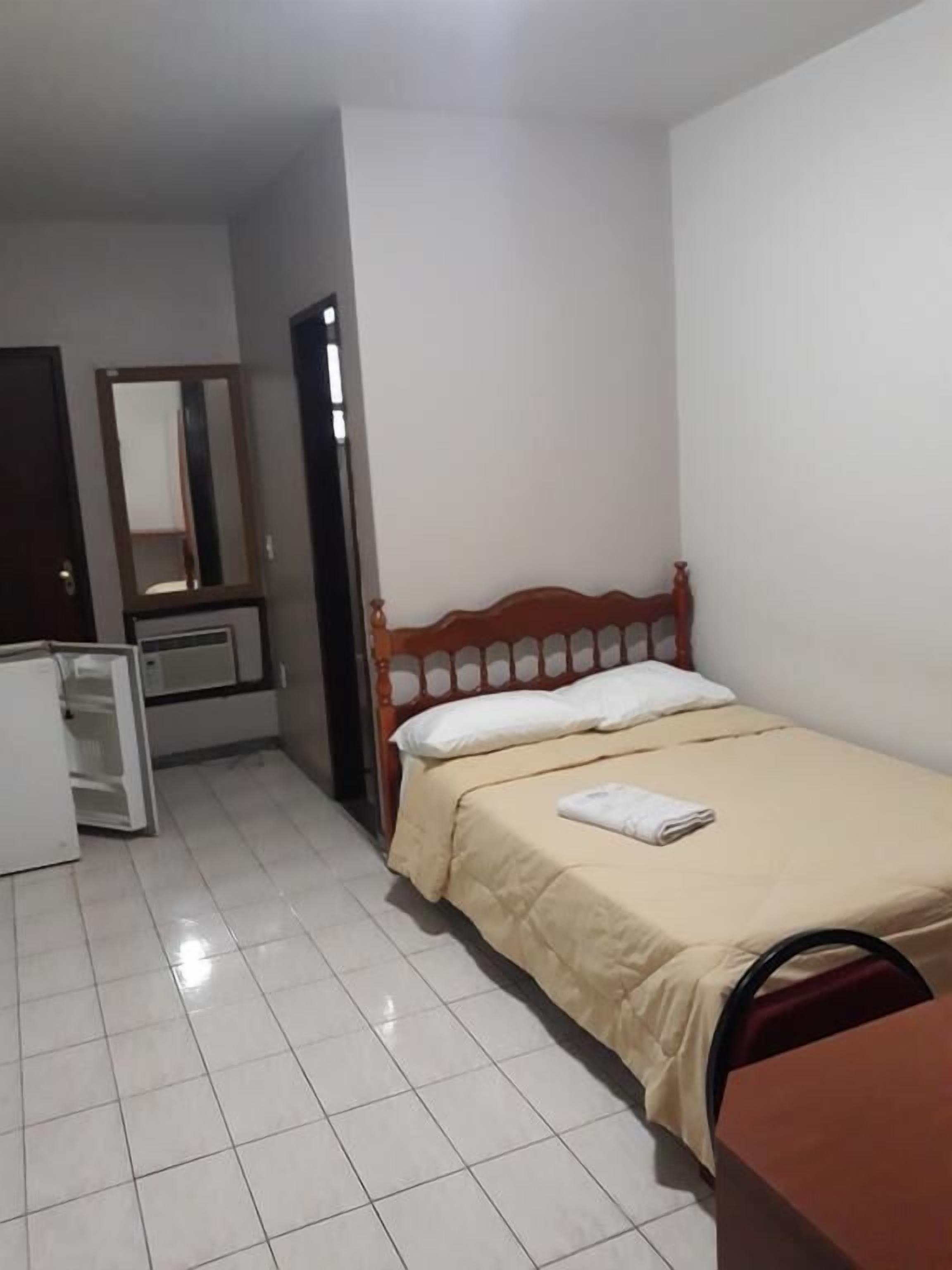 Un dormitorio con cama, cómoda, espejo y puerta.