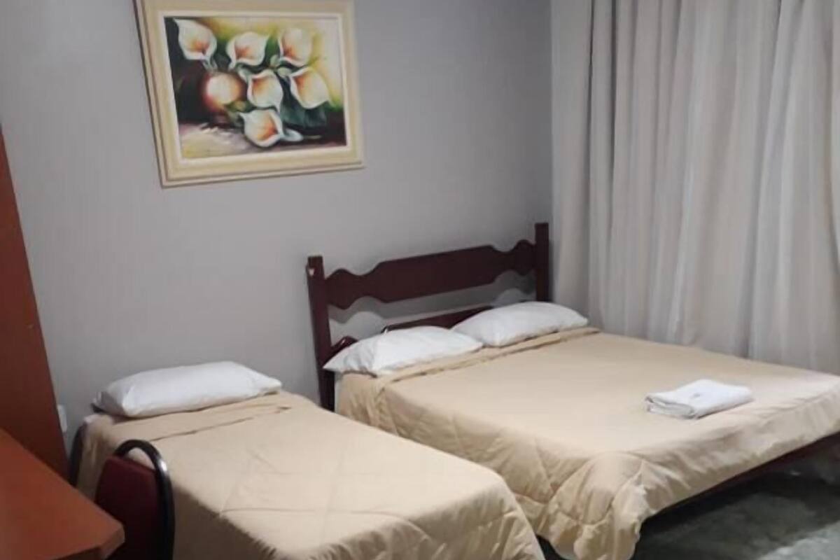 A hotel room with two beds, a desk, and a painting on the wall.
