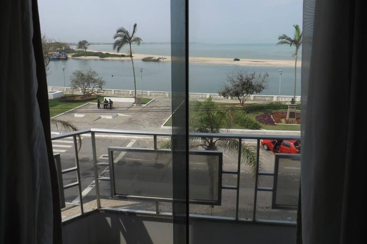 A balcony with a view of a beach and palm trees.