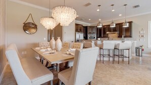 A modern dining area with a large table, multiple chairs, and decorative vases. - Magical Family Getaway | Newly Renovated (Jan 2021), Sunset Golf Course Views,West-Facing Pool (Kissimmee)