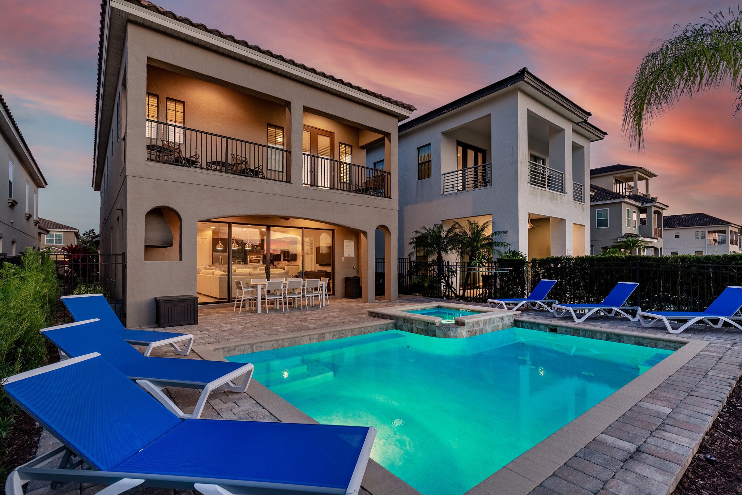A modern two-story house with a swimming pool, outdoor seating, and a well-lit patio area.