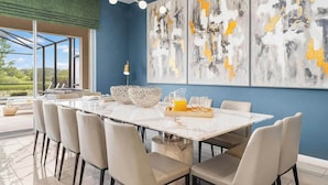 Un comedor moderno con una gran mesa, sillas y arte abstracto en la pared.