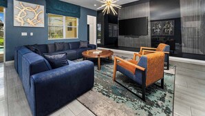 A modern living room with a sectional sofa, a coffee table, and two armchairs. - Grand Home w/ Princess & Wizard Themed BRs, Theater, Arcade & Pool - Near Parks (Davenport)