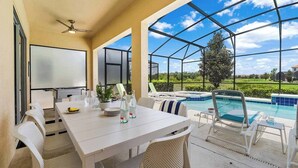 A patio with a table and chairs, a pool, and a view of the landscape. - Grand Home w/ Princess & Wizard Themed BRs, Theater, Arcade & Pool - Near Parks (Davenport)