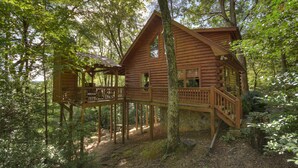 A wooden cabin with a deck, surrounded by trees in a forest. - Pate`s Escape - Cherry Log (Cherry Log)