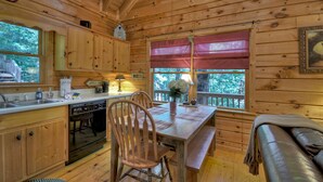 A wooden cabin interior with a kitchen, dining area, and a bench. - Pate`s Escape - Cherry Log (Cherry Log)