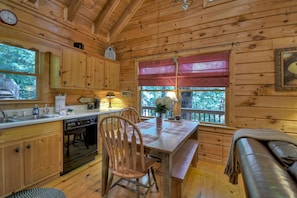 A wooden cabin interior with a kitchen, dining area, and a bench. - Pate`s Escape - Cherry Log (Cherry Log)