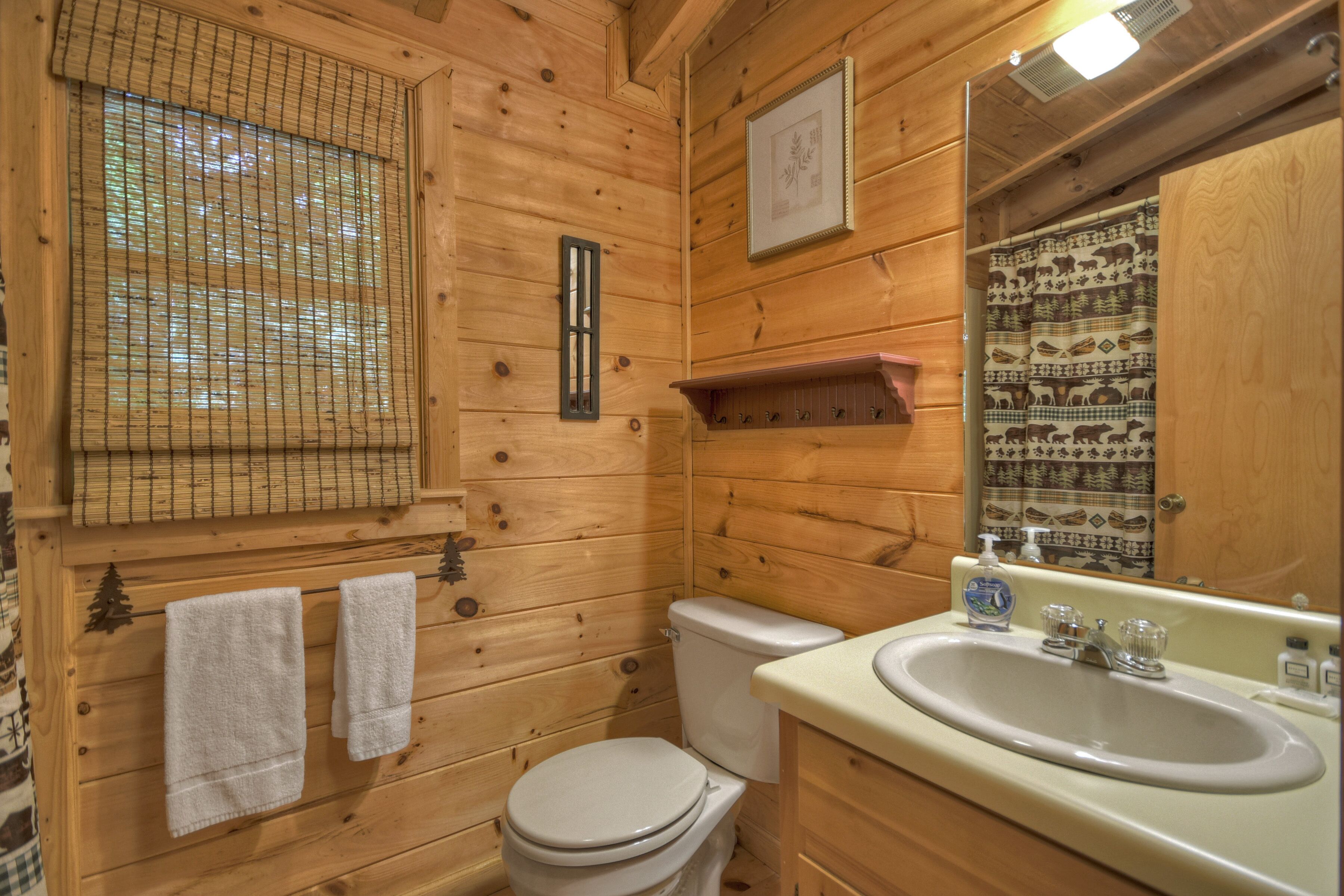 A wooden bathroom with a toilet, sink, and towel rack.