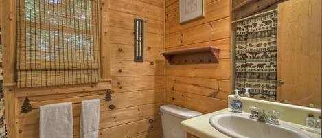 A wooden bathroom with a toilet, sink, and towel rack.