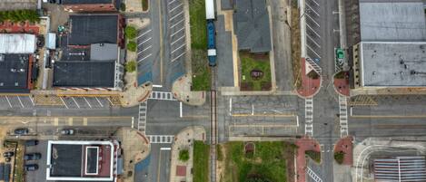 An aerial view of a city intersection with multiple lanes, parking spaces, and buildings.