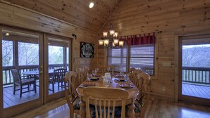 A wooden cabin dining room with a large table set for six, surrounded by chairs.