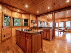 Una cocina espaciosa con paredes de madera y una isla grande, que cuenta con encimeras de granito y amplios armarios.
