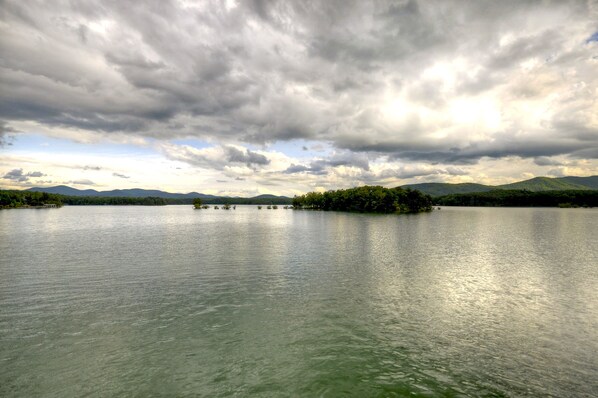 A calm lake with a forested island in the center, surrounded by mountains under a cloudy sky. - Blue Ridge Lake Retreat - Lake Blue Ridge (Blue Ridge)