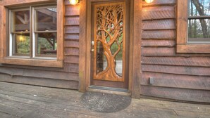 Eine Holzhütte mit einem großen Fenster, einer türmechenden Tür und einer Veranda.