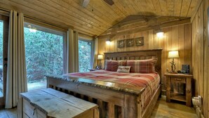 Ein Schlafzimmer einer Holzhütte mit einem Bett, einem Nachttisch und einer Bank.