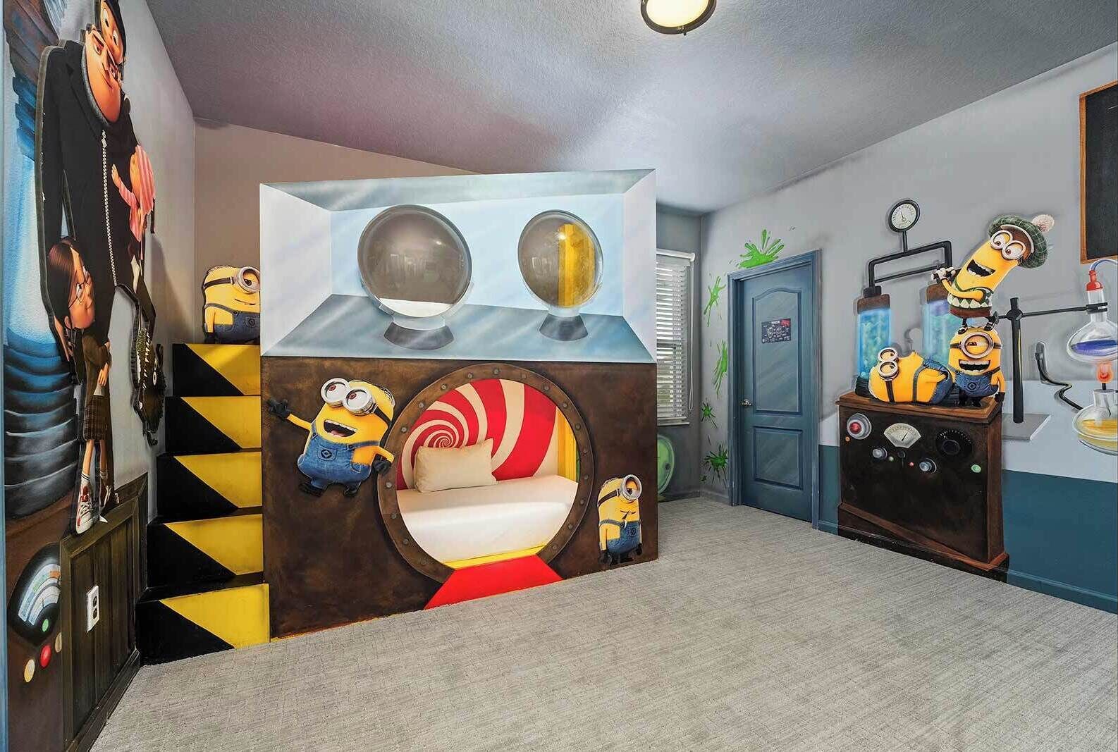 Una habitación con un mural temático de Minions, una cama con diseño circular y un escritorio con una lámpara y una figurita de Minion.