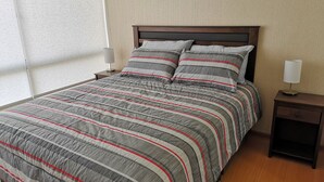 A neatly made bed with striped bedding, a wooden headboard, and two bedside tables with lamps. - LIMA FLAT 8 1D BETWEEN AIRPORT AND MIRAFLORES (Cercado de Lima)