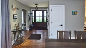 A spacious living area with a wooden floor, a dining table, and a staircase leading to another level.