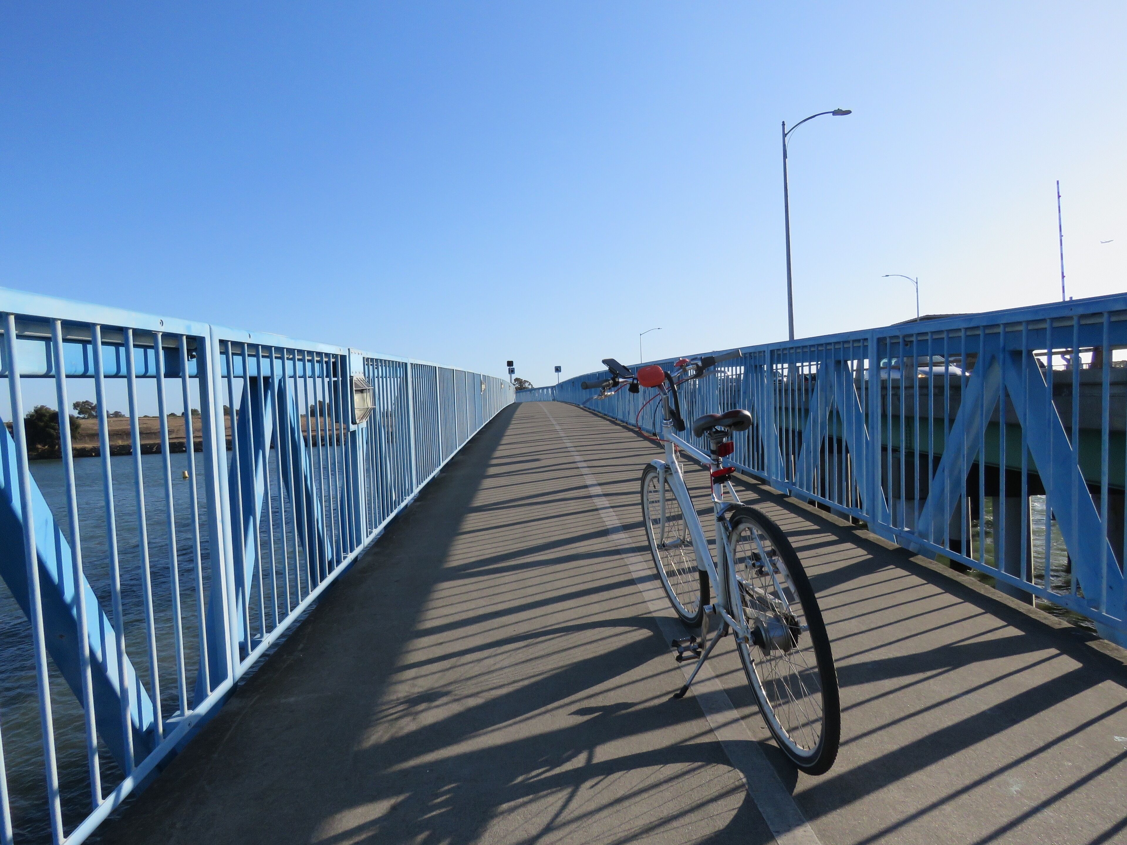 Uma bicicleta estacionada em uma ponte com guarda-corpo azul.