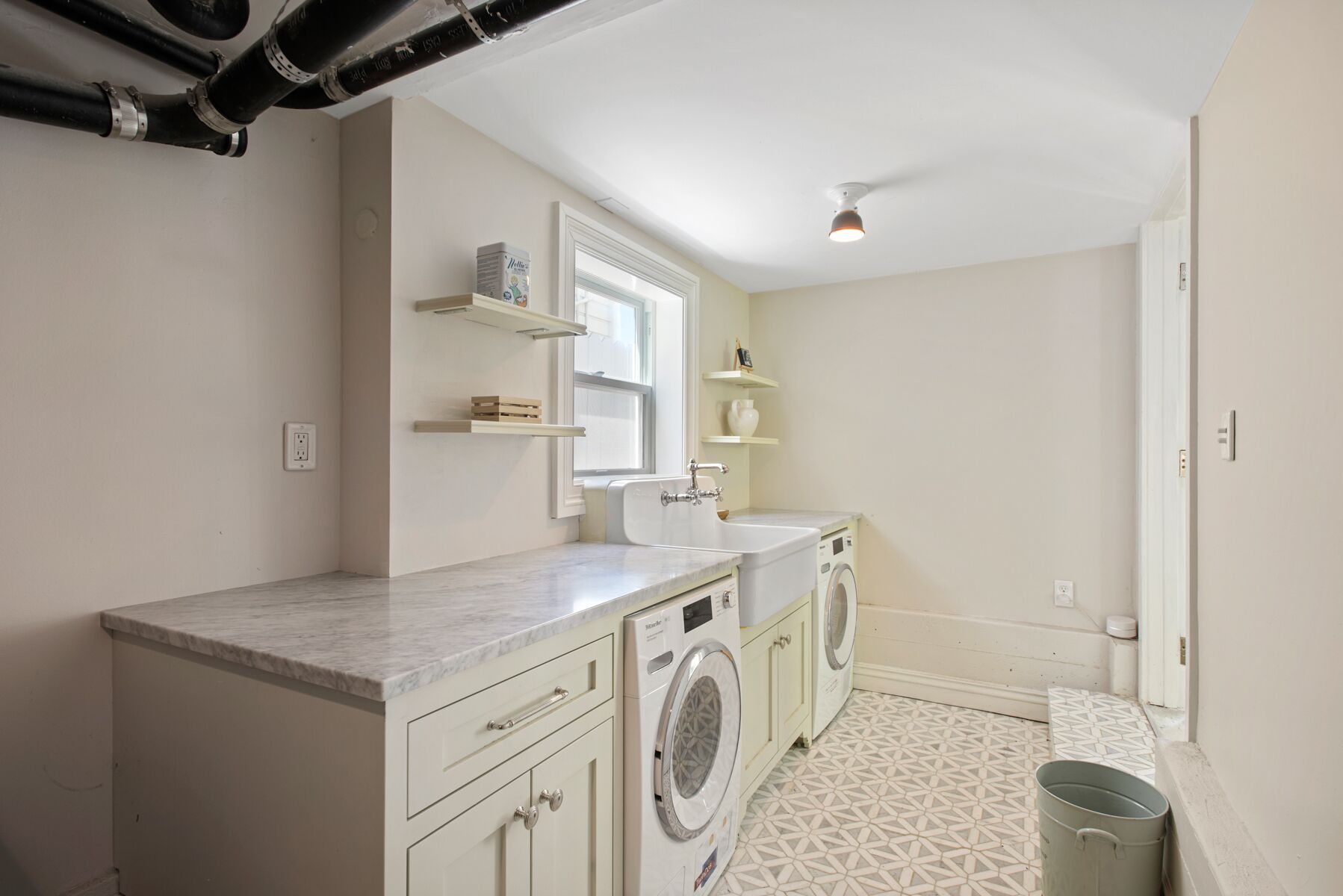 A compact laundry room with a washing machine, dryer, and a sink.