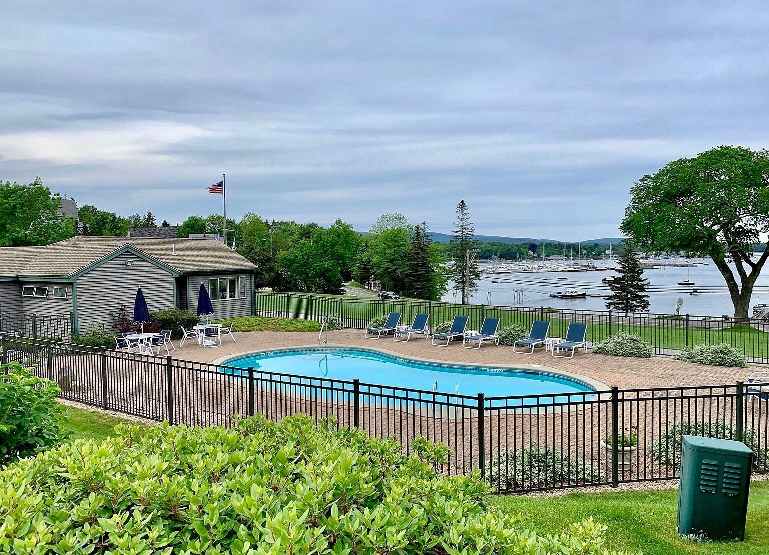 A swimming pool with lounge chairs and a view of a marina.