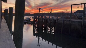 A waterfront dock with boats, a wooden pier, and a sunset in the background. - Best views on MDI - 2 bedroom 2 bath condo - waterfront with in ground pool (Southwest Harbor)