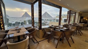 A restaurant with a view of the pyramids, featuring a modern interior with leather chairs and a wooden table. - Sahara Pyramids Inn (Giza)