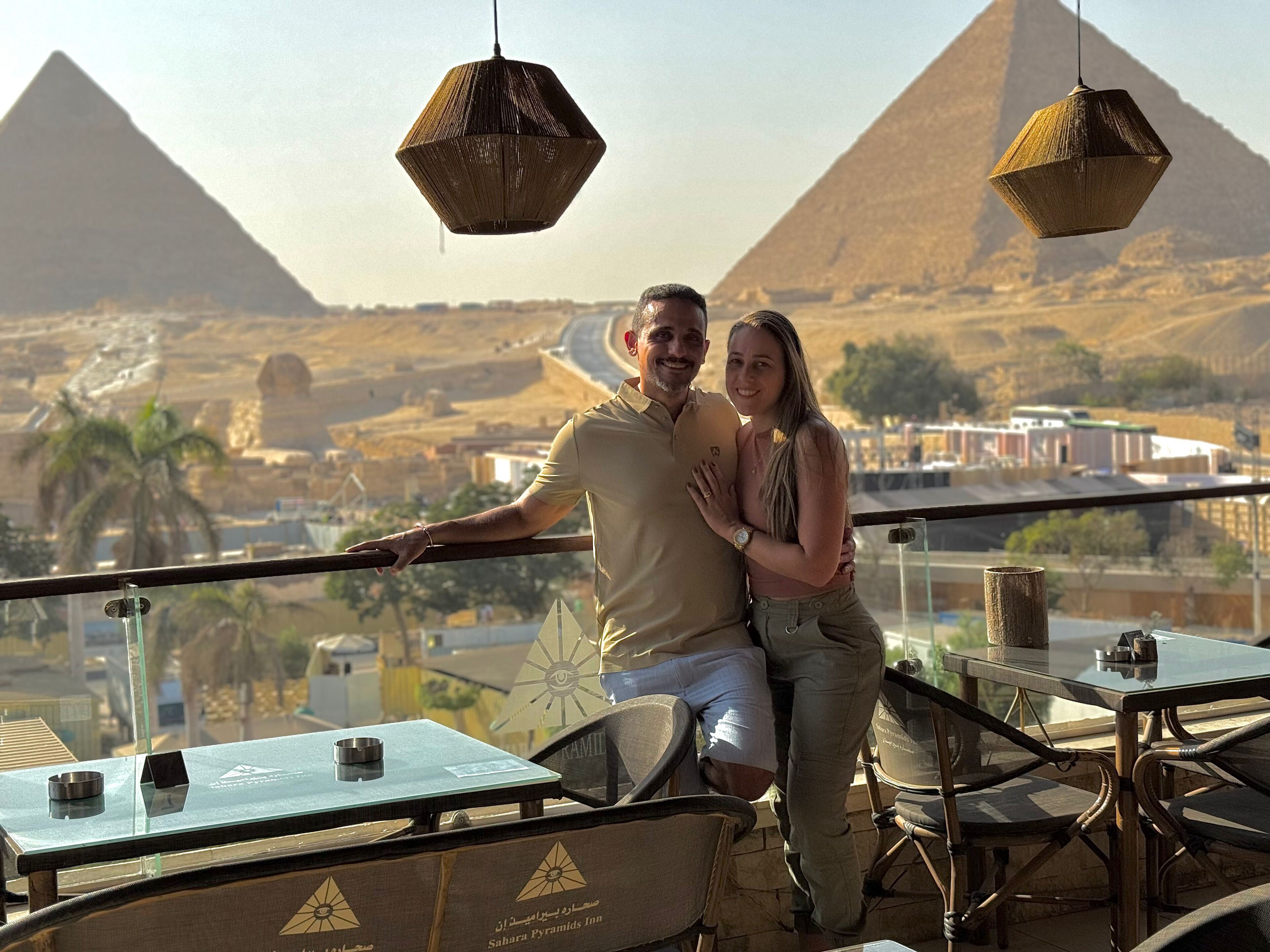Un couple sur un balcon avec vue sur les pyramides.
