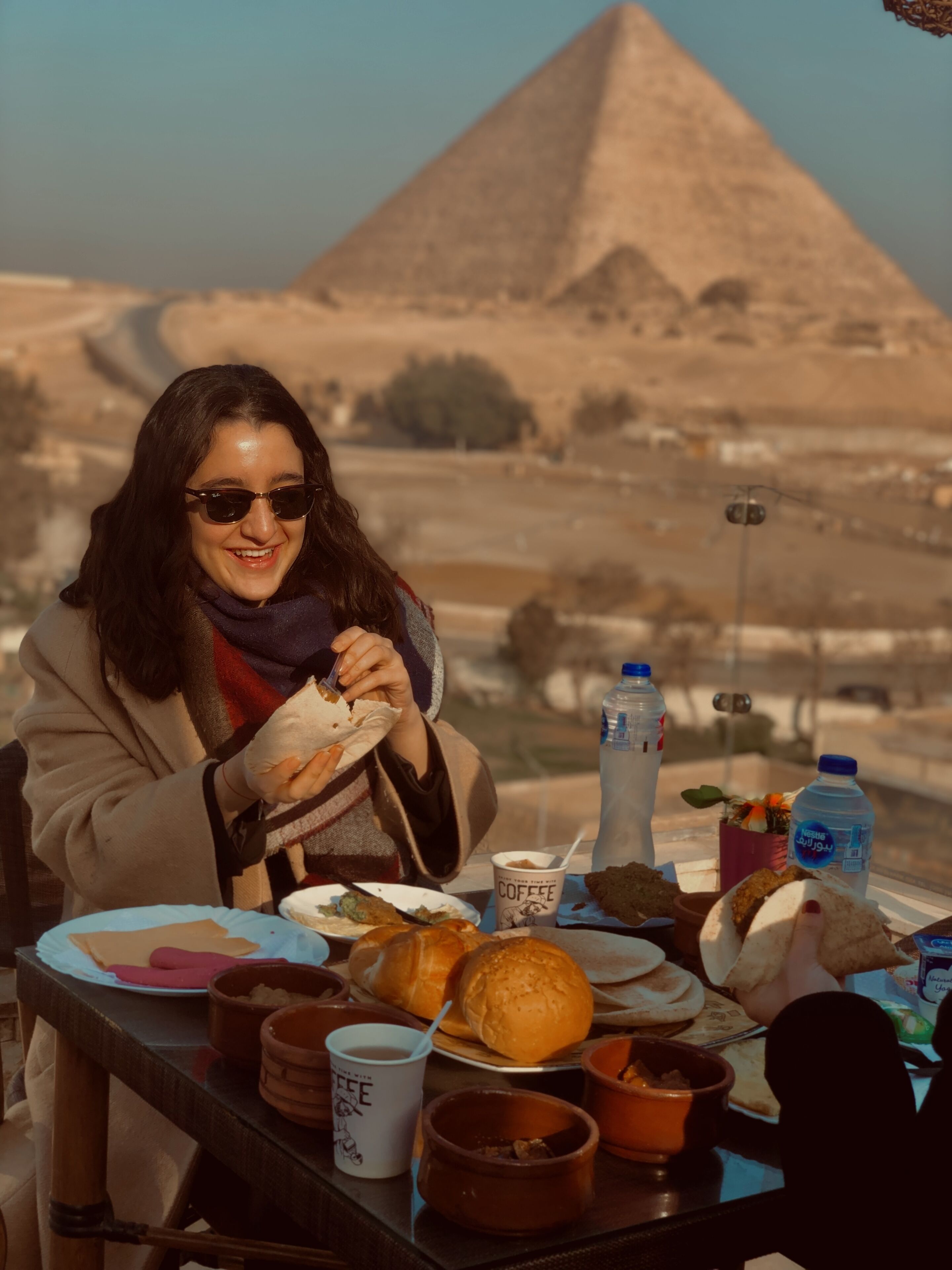 A person dining at a table with a view of the pyramid in the background.