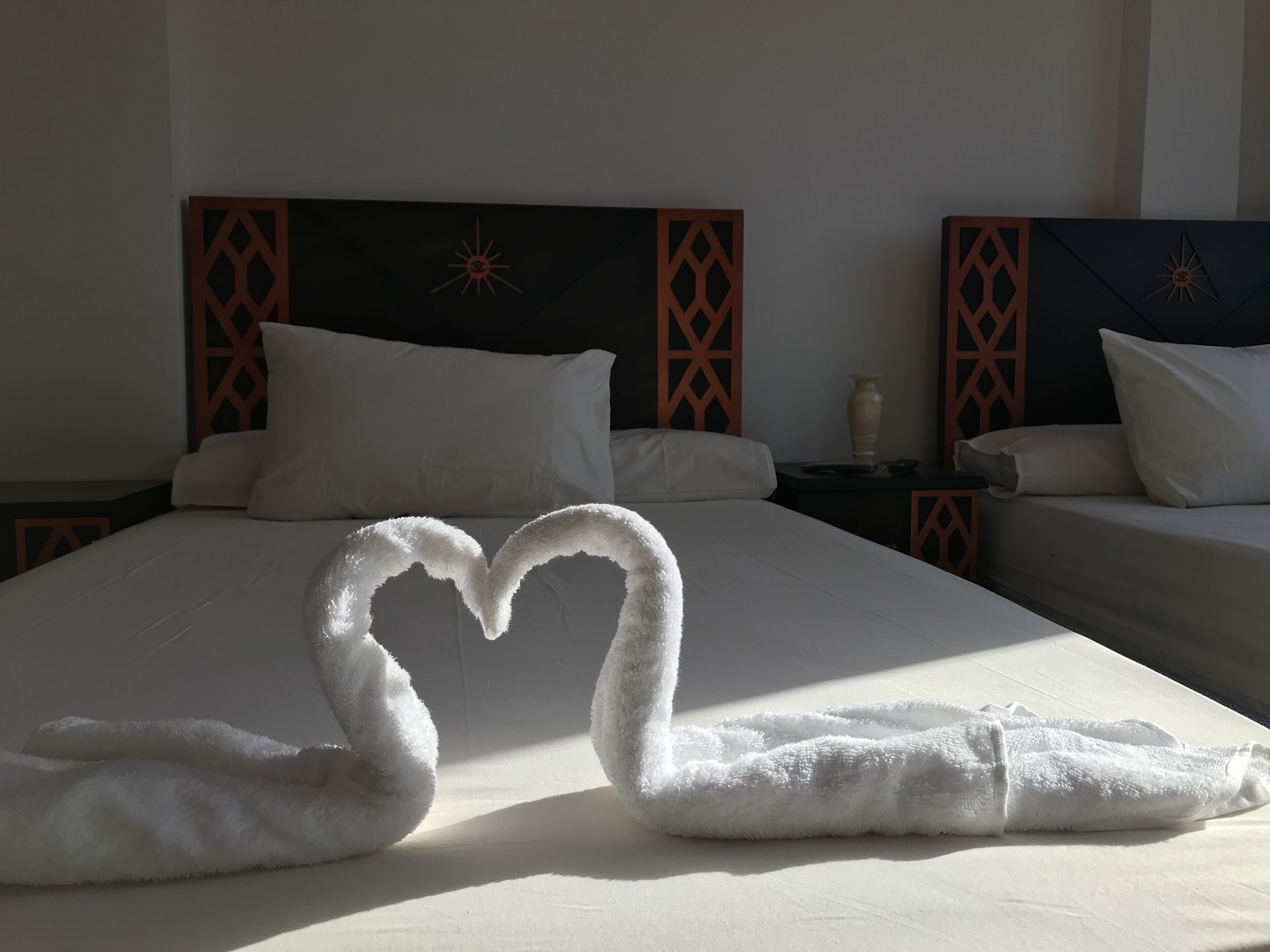 A hotel room with a large bed, two bedside tables, and a decorative wall panel.