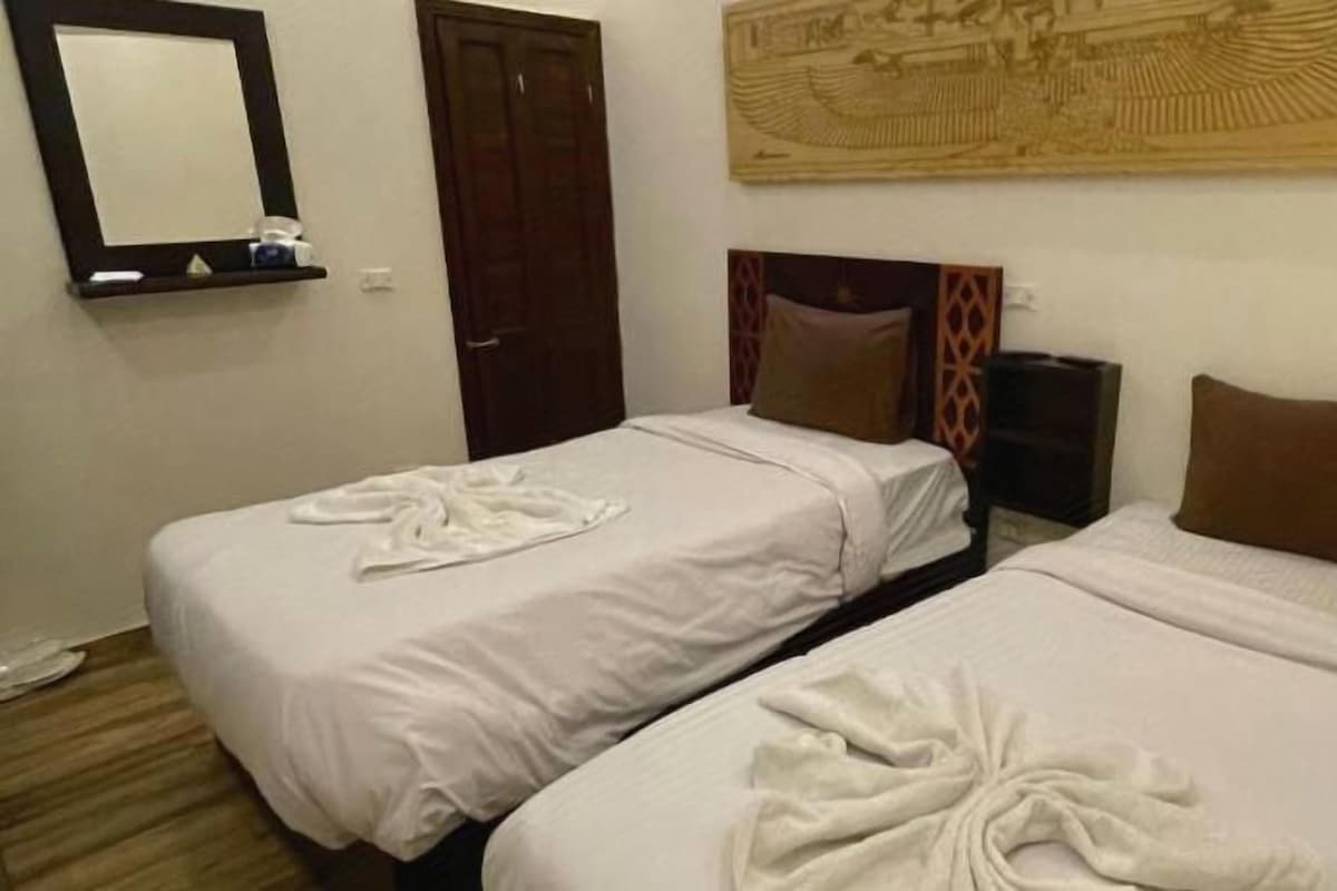 Ein Hotelzimmer mit zwei Betten, einer Holztür, einem Spiegel und einem Wanddekor.