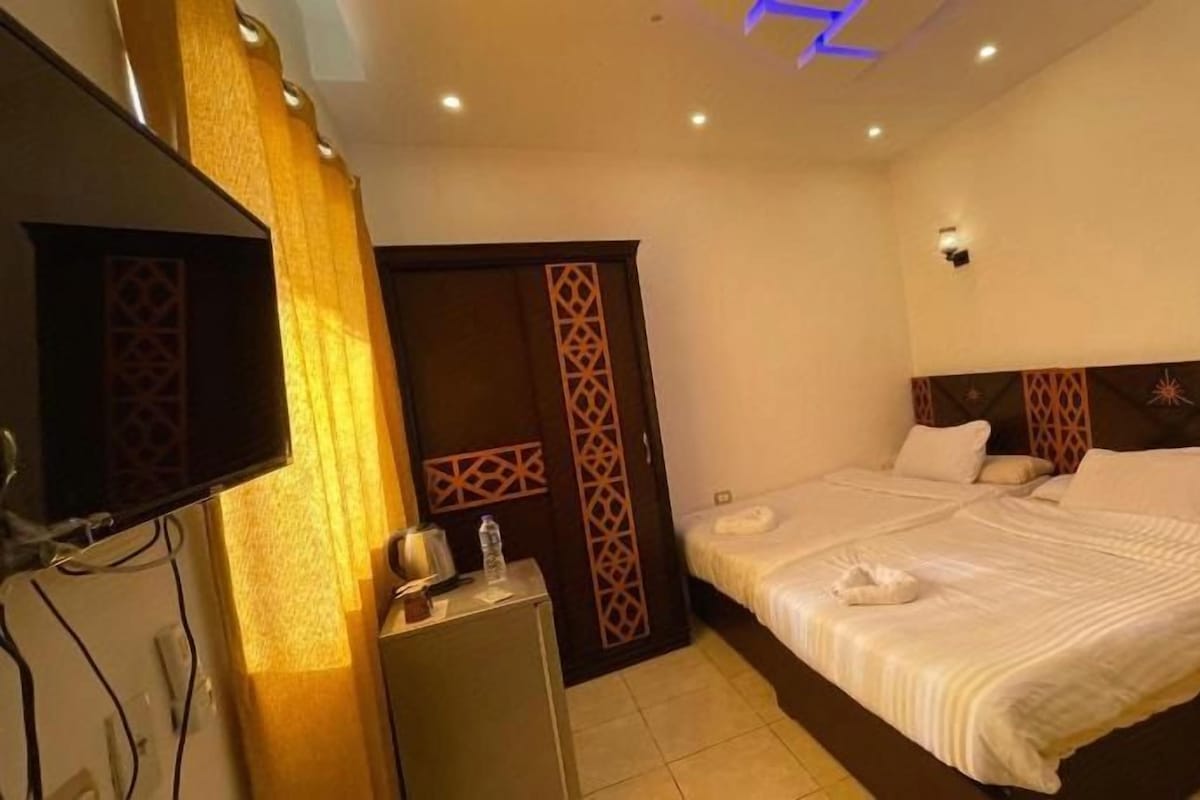Ein Hotelzimmer mit Bett, Fernseher, Nachttisch und Kleiderschrank.