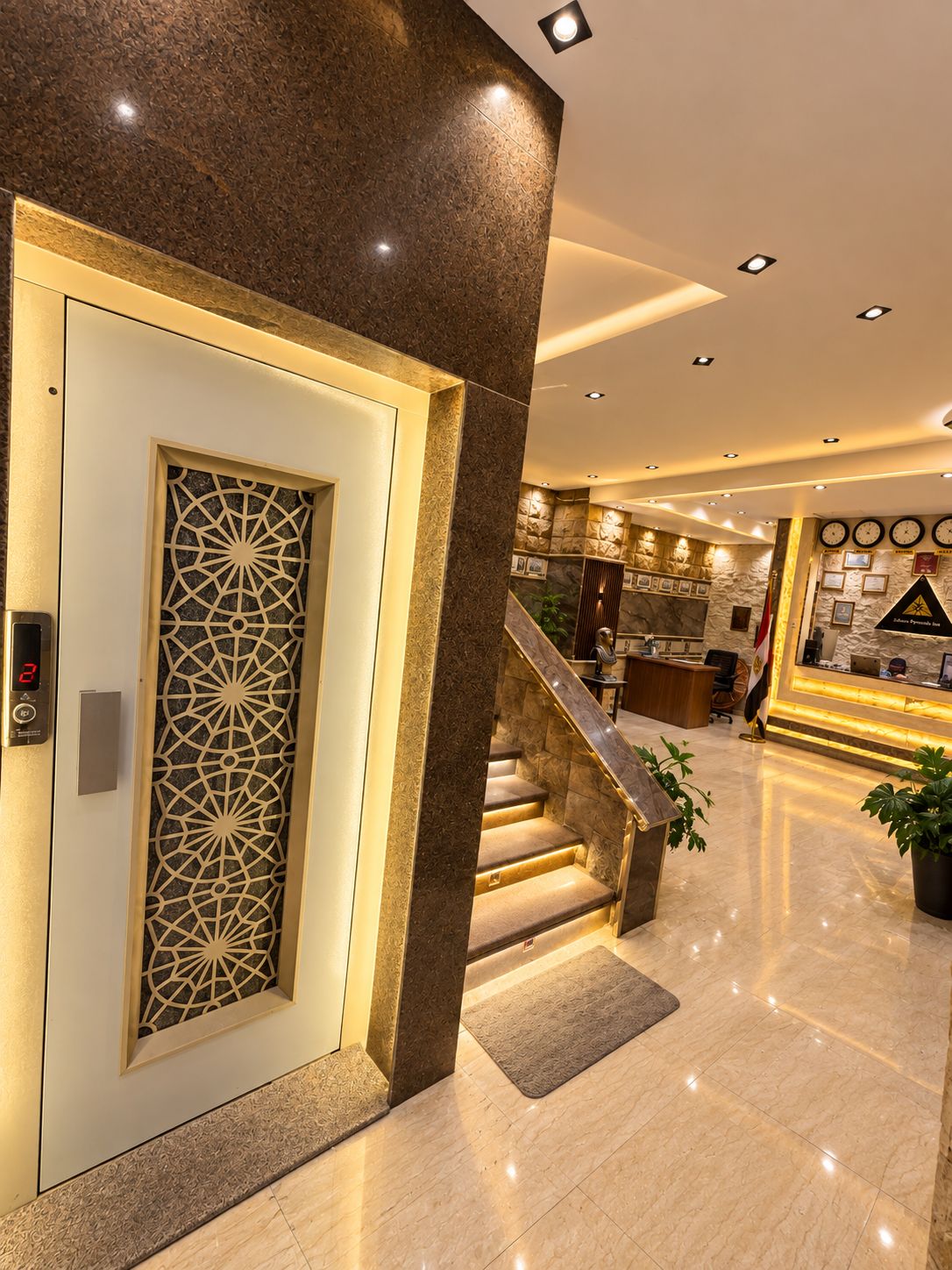 Eine Hotelhalle mit einer Rezeption, einer Treppe und einer Wand mit gerahmten Bildern.