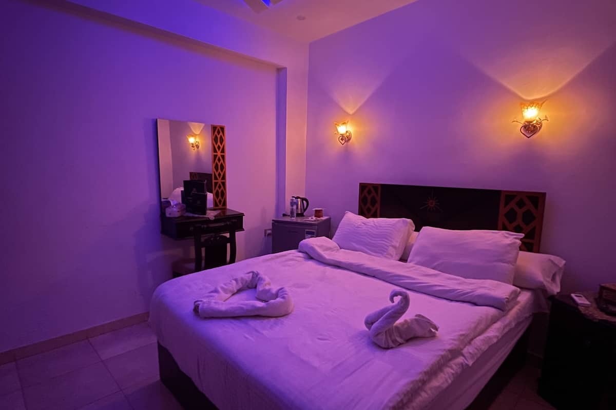 A modern bedroom with a large bed, two wall-mounted lights, and a ceiling light.