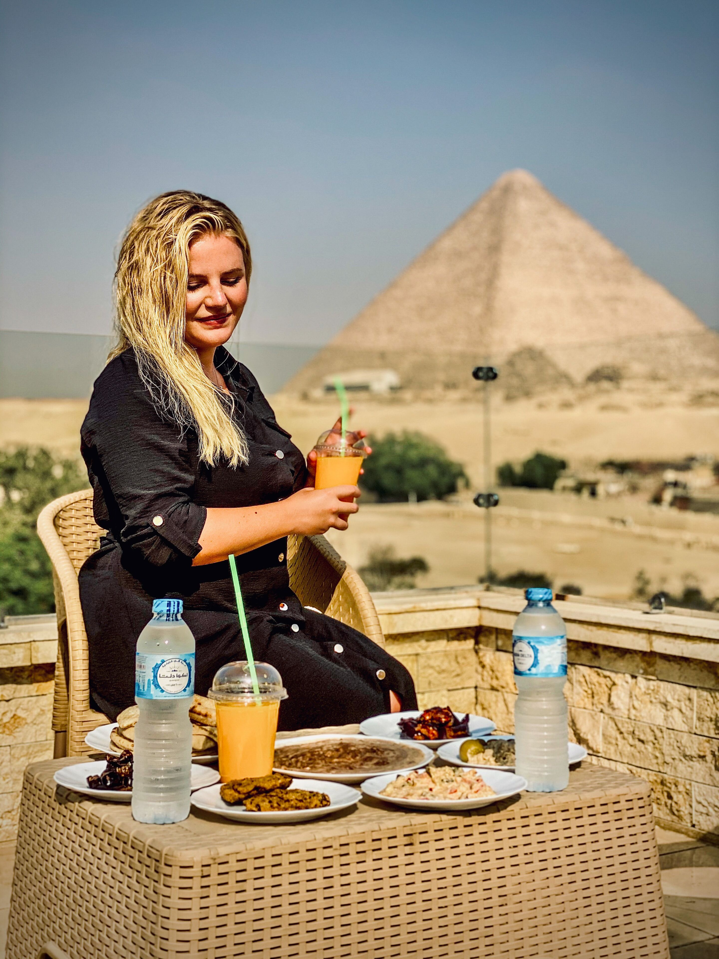 Eine Person sitzt an einem Tisch mit Blick auf eine Pyramide im Hintergrund.