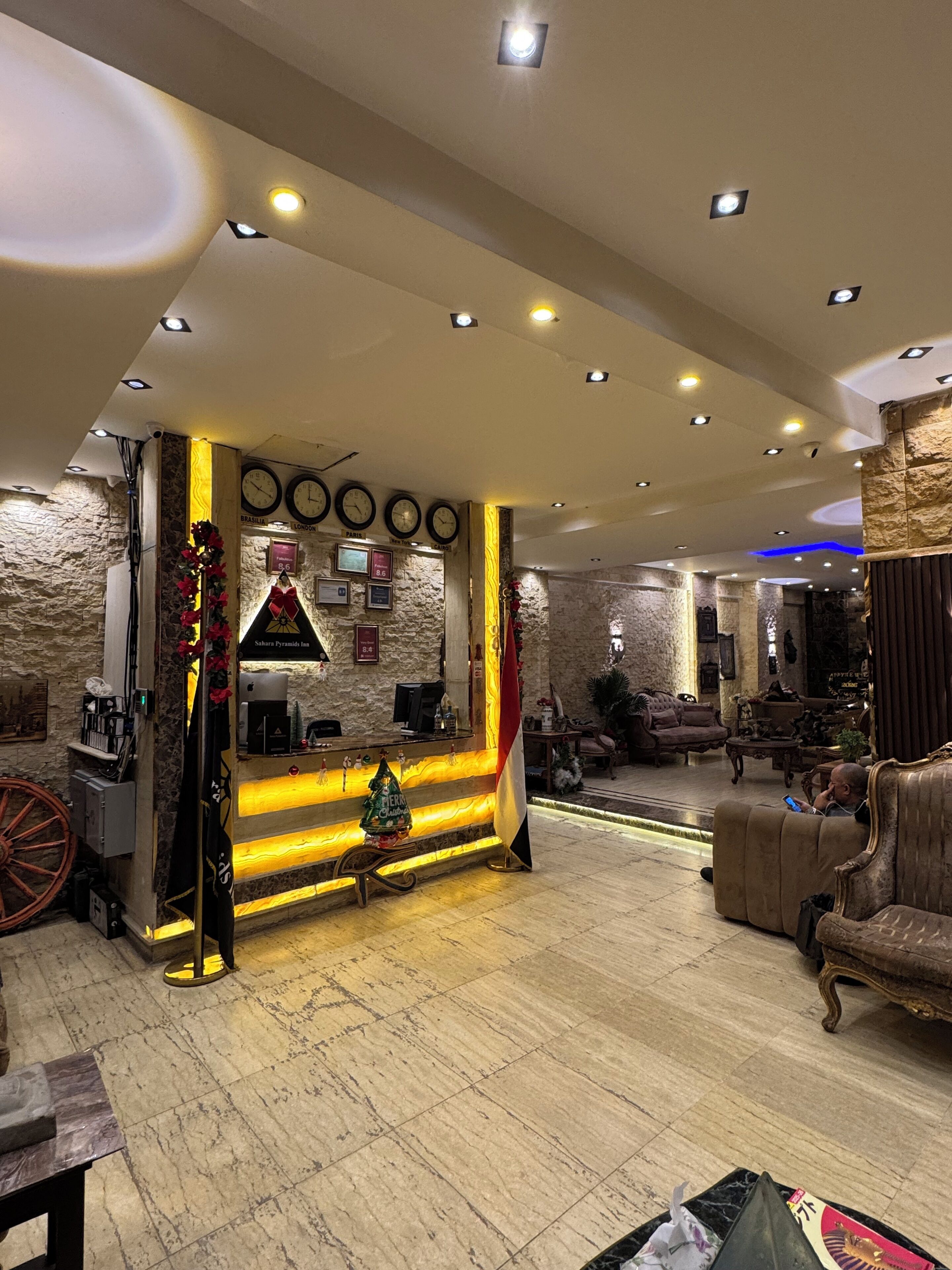 A lobby with a reception desk, clocks, and a stone wall.
