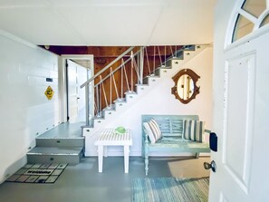 Staircase leads to an upper level with a table and bench at the base.