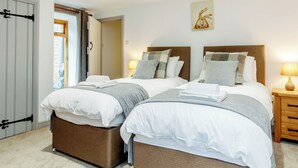 A double bed with a wooden headboard, a bedside table with a lamp, and a door with a black handle. - The Old Granary - UK12135 (Hewelsfield, near Lydney)