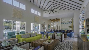 A spacious living area with a high ceiling, large windows, and a modern kitchen in the background. - Veranda Palms 8 Bedroom Home with Pool(2208) (Kissimmee)