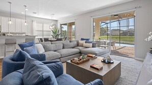 A spacious living area with a large sectional sofa, a coffee table, and a view of the outdoors through large sliding glass doors. - Veranda Palms 8 Bedroom Home with Pool(2208) (Kissimmee)