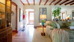 Amplia sala de estar con techo de madera, un sofá grande, una mesa de centro y una planta en maceta.